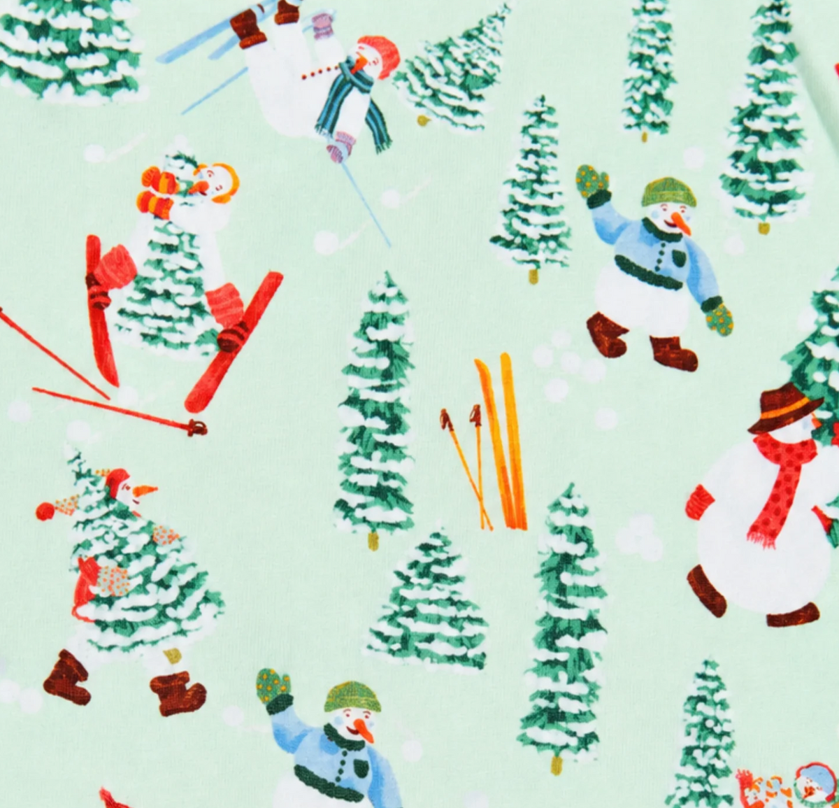 A close-up of a light mint green fabric with a repeating winter ski pattern featuring snowmen, pine trees, skis, and red boots.