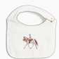 An off-white fabric baby bib with a scalloped edge and a central embroidered design of a horse and rider, shown on a plain white background.