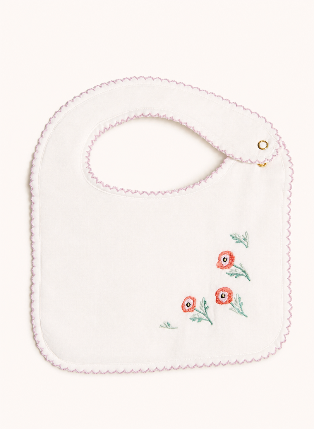 An off-white cotton baby bib with a scalloped pink border, featuring three embroidered red poppies with green leaves on the lower right and a gold snap button on the neck strap.
