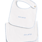 A white baby bib and matching footie cloth set with light blue scalloped edges and the word 'amore' embroidered in blue on each piece, shown on a warm off-white background.