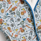 A close-up of a light blue fabric garment with a multicolor sports-themed print featuring basketballs, soccer balls, lacrosse sticks, rackets, and balls, finished with a white plush lining and blue piping.