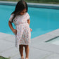 Young girl in a floral dress standing by a pool