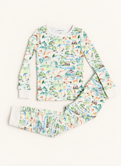 A two-piece children's pajama set from Uppsalund, featuring a long-sleeve top and matching pants with a colorful watercolor-style camping and forest print on a white background.