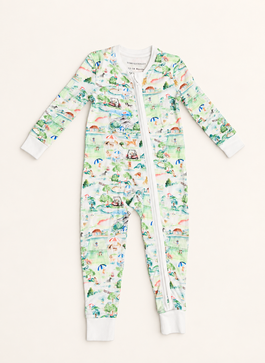 A baby long-sleeve footless zip-up one-piece pajama with an all-over illustrated print in pastel green, blue, pink, and orange on a white base, shown flat against a light cream background.