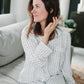 Woman wearing a textured robe sitting on a couch in a living room.