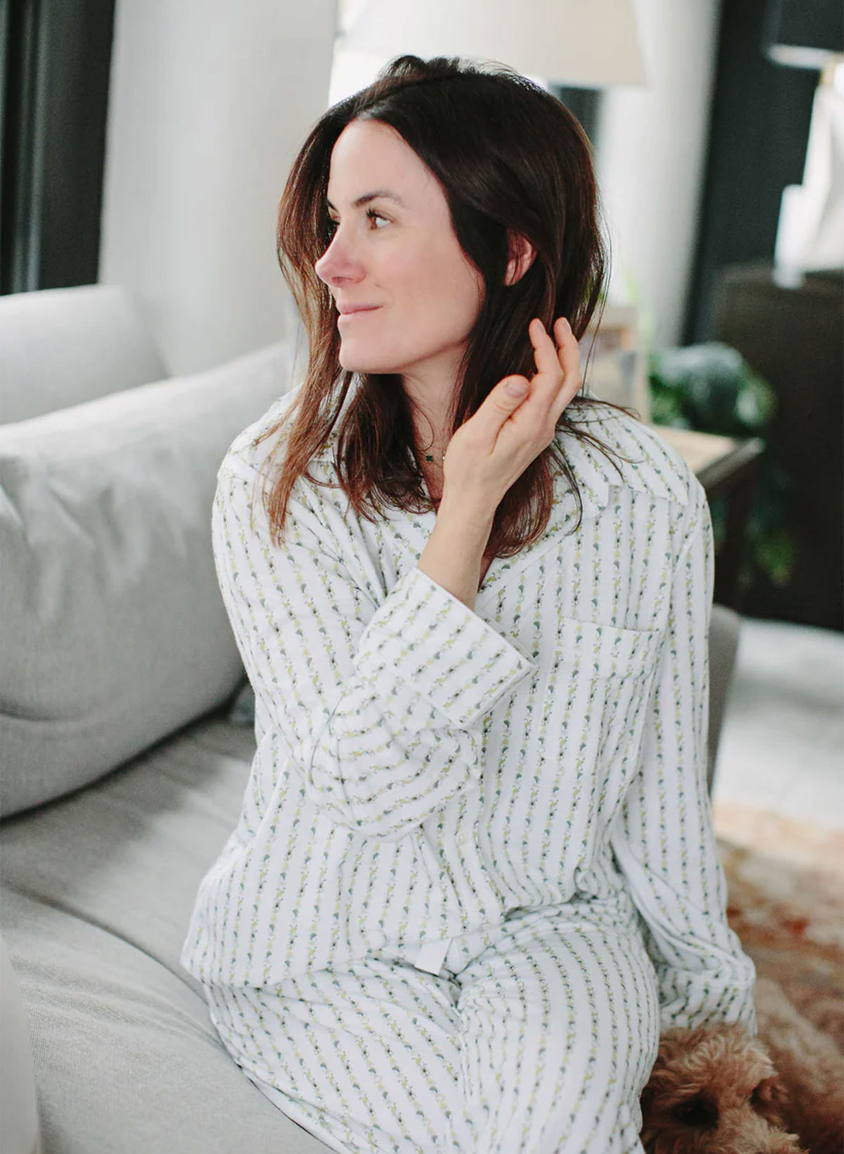 Woman wearing a textured robe sitting on a couch in a living room.