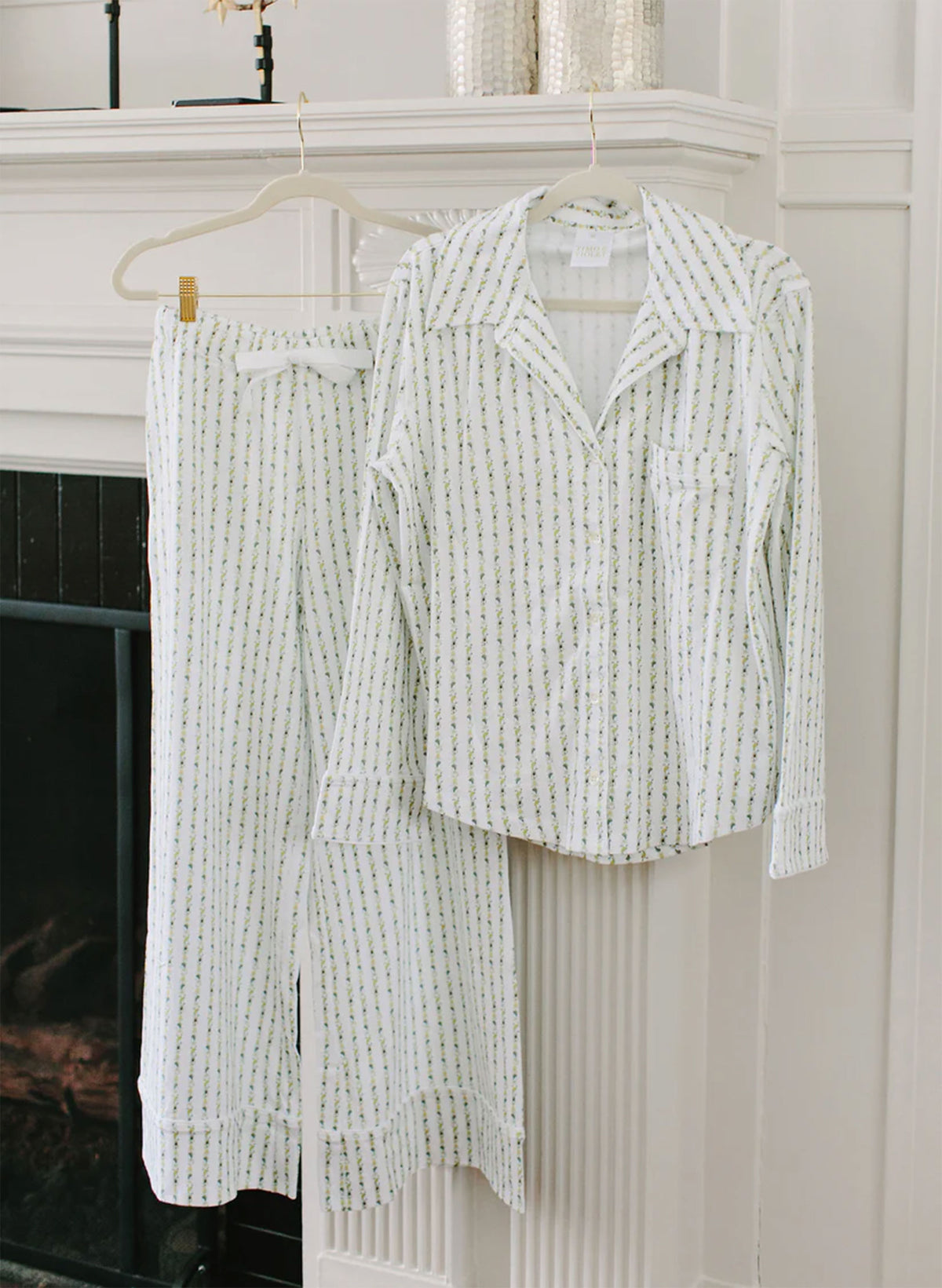 White textured shirt and pants hanging on a hanger against a white wall.