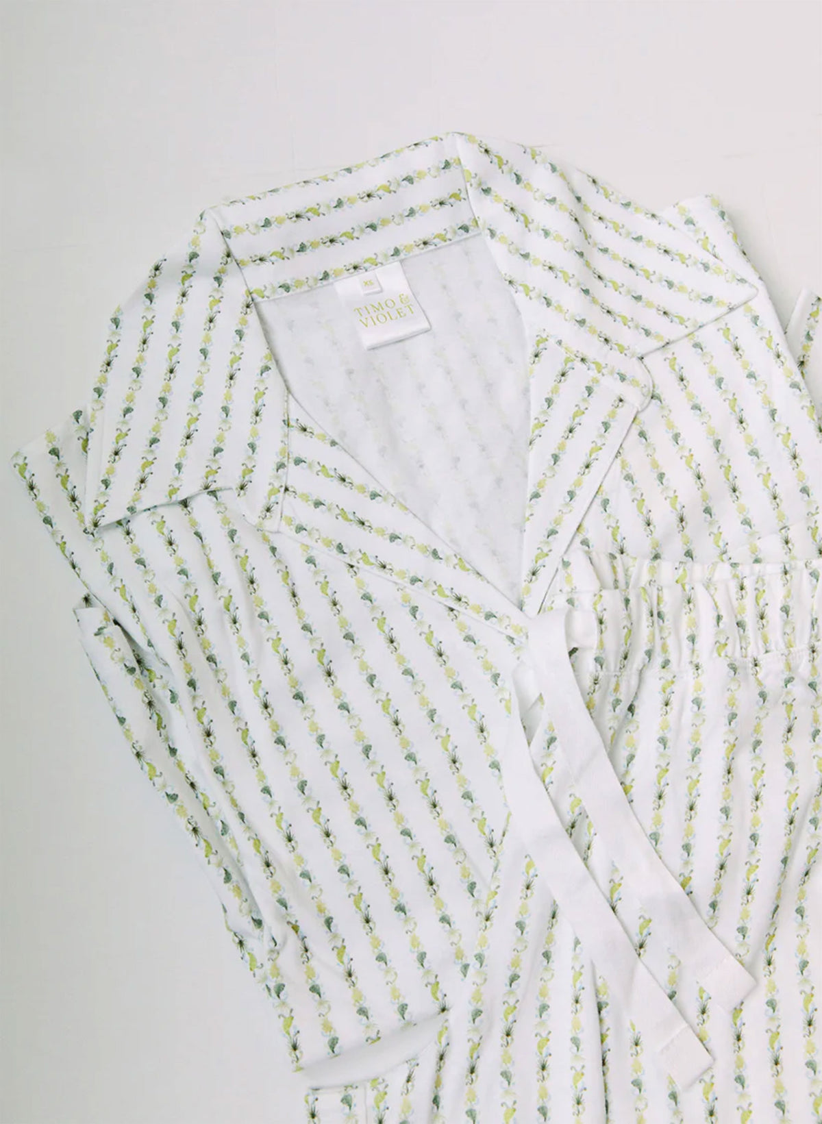 White robe with green floral pattern on a light gray background