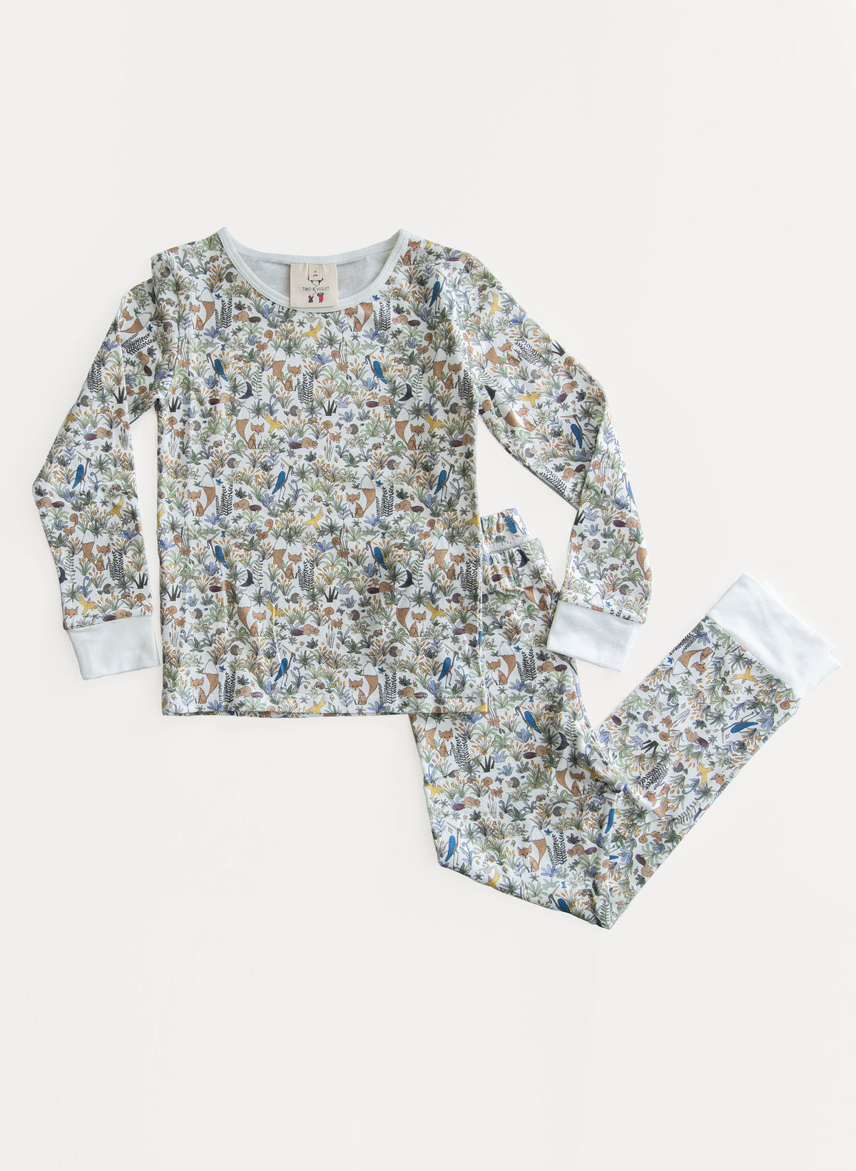 A children's long-sleeve pajama set with matching pants, featuring an all-over woodland animal print in muted blue, brown, and beige tones on a light background, with solid light blue cuffs.