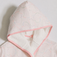 A close-up of a girl's hooded robe or towel set in a very light pink fabric with a subtle tonal cloud pattern, featuring a contrasting soft pink inner lining and trim.
