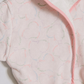 A close-up of a plush white bathrobe with a soft pink border and a subtle, tonal heart pattern.