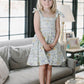 Young girl in a floral dress standing in a living room.
