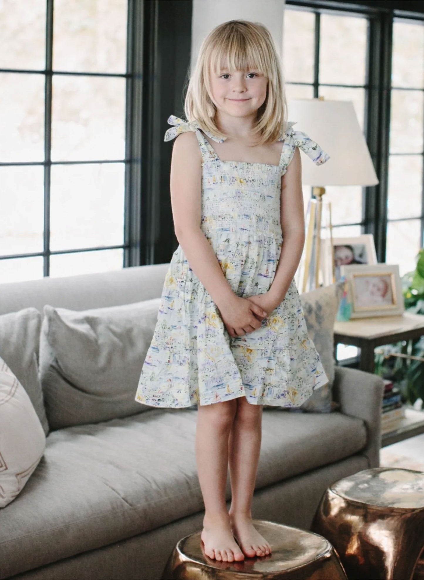 Young girl in a floral dress standing in a living room.