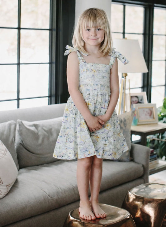 Young girl in a floral dress standing in a living room.