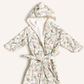 A hooded bathrobe with a white sherpa lining and a delicate multicolor floral print, tied at the waist, laid flat on a light cream background.