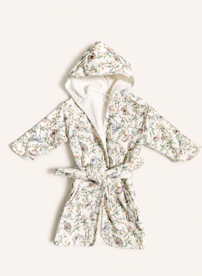 A hooded bathrobe with a white sherpa lining and a delicate multicolor floral print, tied at the waist, laid flat on a light cream background.