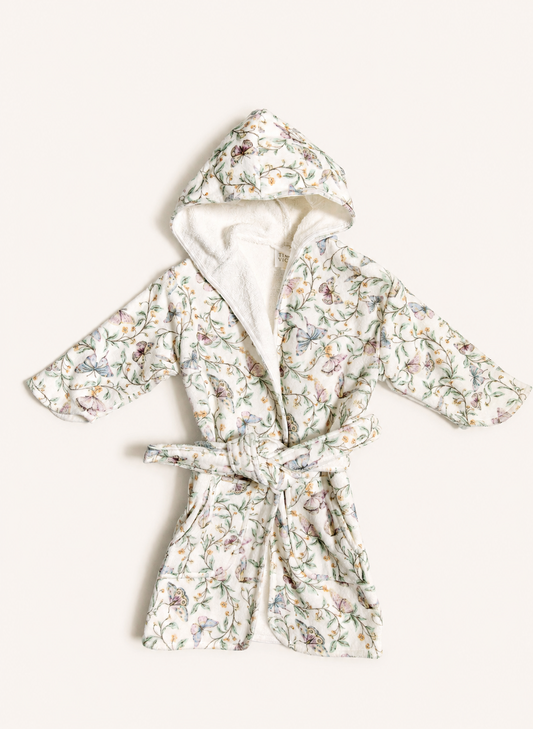 A hooded bathrobe with a white sherpa lining and a delicate multicolor floral print, tied at the waist, laid flat on a light cream background.