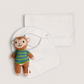 A set of two white baby bibs with light blue scalloped edges, one laid flat and one hanging, featuring the embroidered brand name 'anore'. A small plush monkey toy wearing a green and blue striped shirt is tucked into the hanging bib.