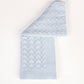A light blue knit blanket with a textured geometric pattern, folded diagonally on a clean white background.