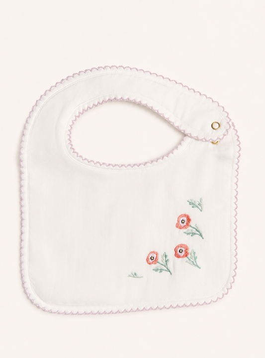 A white baby bib with a scalloped pink border and embroidered pink flowers with green stems on the lower right, shown on a light cream background.