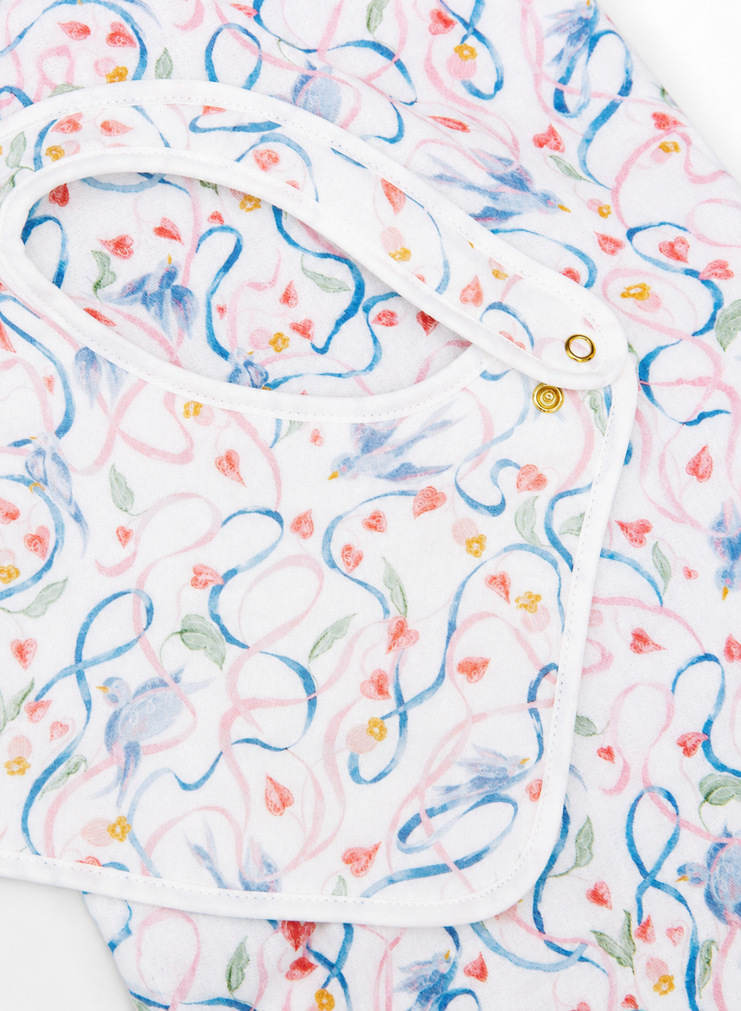 A close-up of a white baby bib with a colorful watercolor-style floral and swirl pattern in blue, pink, and green, featuring white trim and snap closures.
