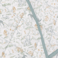 A close-up of a quilted baby blanket featuring a safari animal print with giraffes, lions, and zebras in muted blue, green, and beige tones on a white background, accented by a dusty blue-green border.