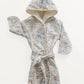 Children's hooded bathrobe with a multicolored animal print and white bias trim, displayed on a white background.