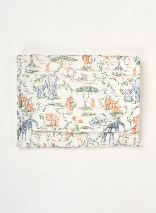 A folded fabric item, likely a blanket or cloth bag, featuring a toile-style safari print with animals and foliage on a cream background.