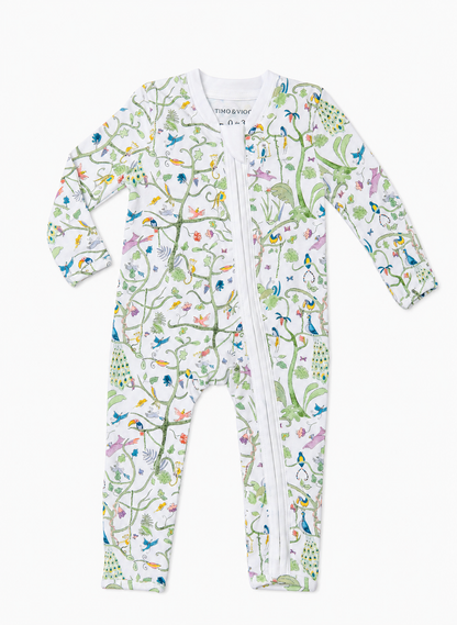 A baby long-sleeve footed sleeper with a white background and a colorful nature print featuring birds, penguins, and trees, complete with a front zipper.
