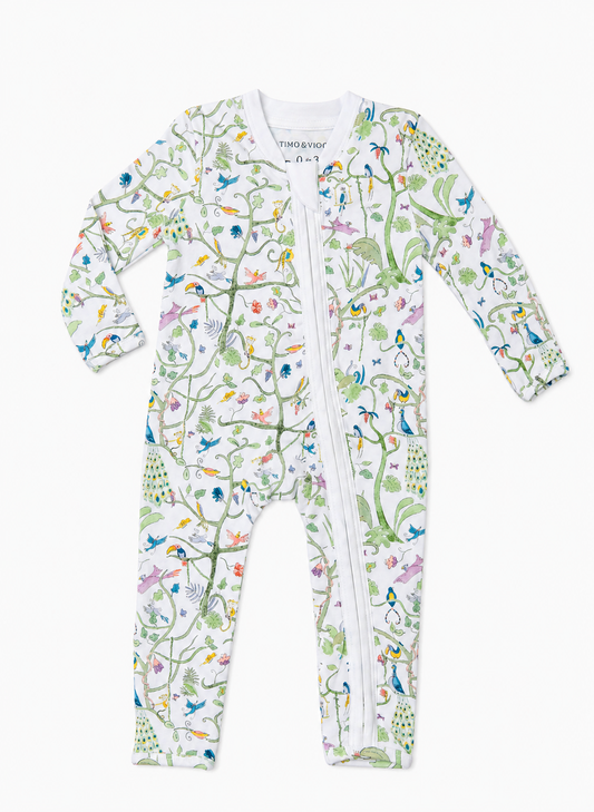 A baby long-sleeve footed sleeper with a white background and a colorful nature print featuring birds, penguins, and trees, complete with a front zipper.