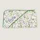 A rectangular quilted baby blanket with a white background, decorated with a colorful nature print of birds, butterflies, and plants, featuring green piping and a diagonal zipper closure.