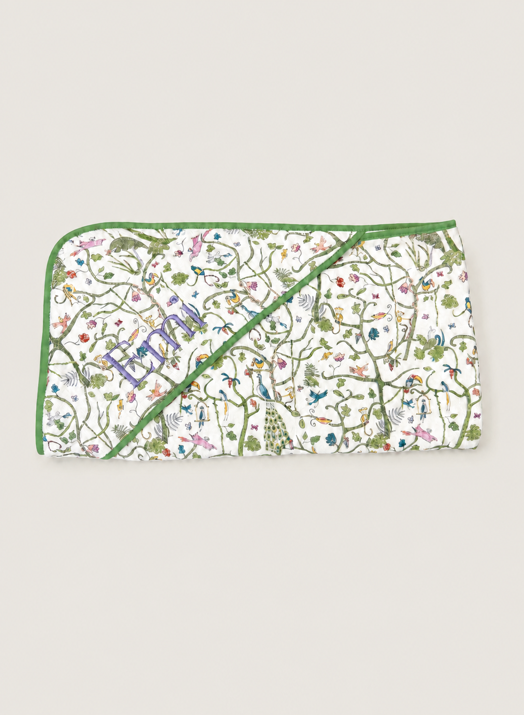 A rectangular quilted baby blanket with a white background, decorated with a colorful nature print of birds, butterflies, and plants, featuring green piping and a diagonal zipper closure.