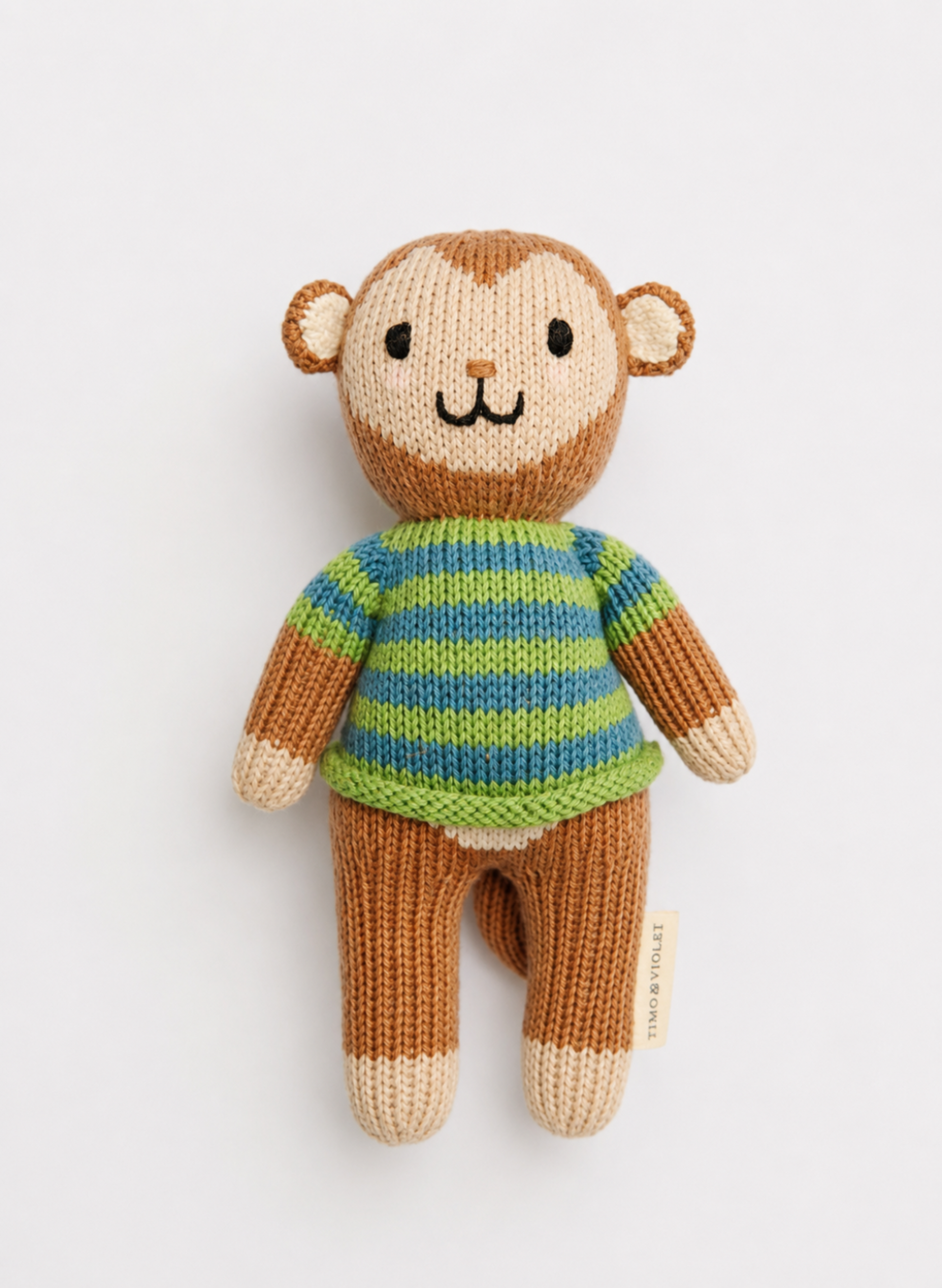 A handmade knitted monkey doll with a brown and beige body, wearing a green and blue striped sweater, photographed against a clean white background.