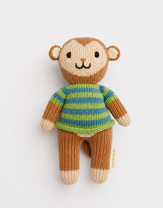 A handmade knitted monkey doll with a brown and beige body, wearing a green and blue striped sweater, photographed against a clean white background.