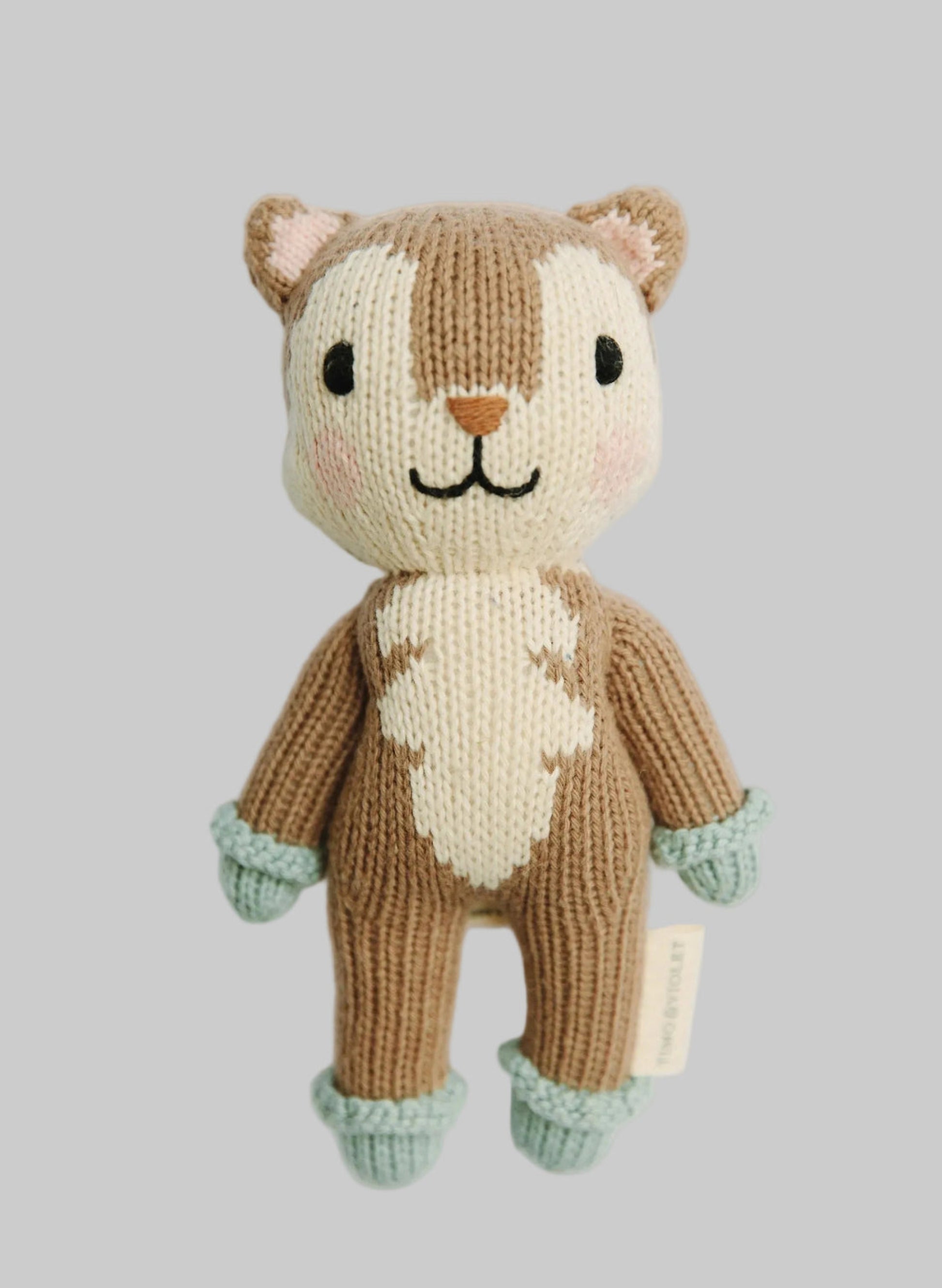 A hand-knitted plush toy of a fox with a brown and cream body, mint green cuffs, and black embroidered facial features, shown against a plain light gray background.