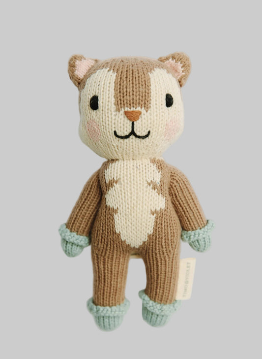 A hand-knitted plush toy of a fox with a brown and cream body, mint green cuffs, and black embroidered facial features, shown against a plain light gray background.