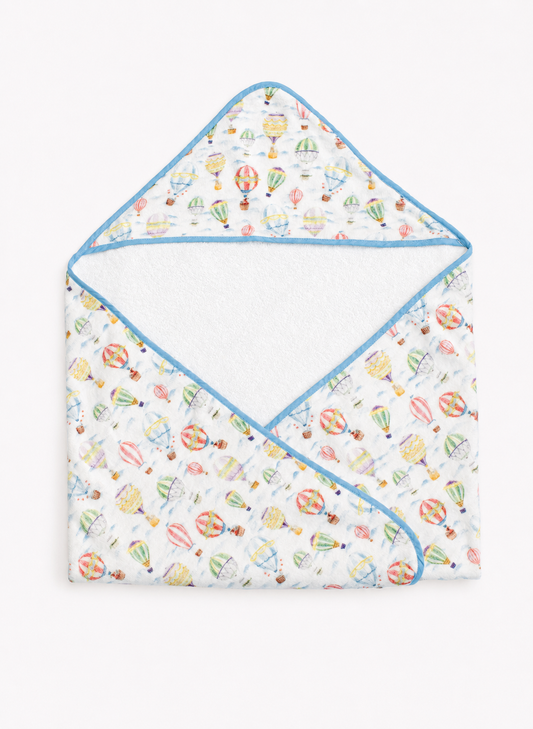 A baby hooded towel with a white background and a colorful hot air balloon pattern, finished with light blue trim.
