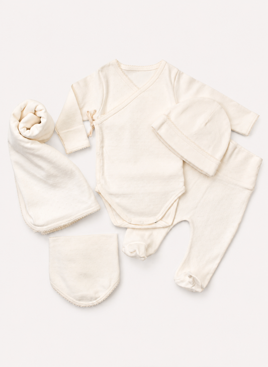 A five-piece baby clothing set in a soft cream or off-white color, including a long-sleeve wrap bodysuit, footed pants, a beanie, a hat, and a bootie, arranged neatly on a light beige background.