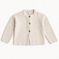 A cream-colored knit cardigan sweater for toddlers, featuring a round neck, raglan sleeves, and three brown buttons down the front. The brand name 'TMC & VLOT' is visible on the inner neck label.
