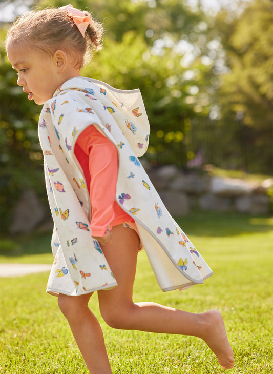 Child wearing a colorful butterfly-patterned hooded jacket in a park setting