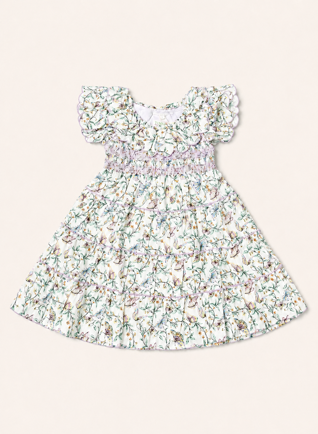 A toddler girl's dress with a white base and a delicate multicolor floral print, featuring ruffled cap sleeves and a smocked waist, shown flat on a light beige background.