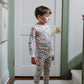 Child wearing a floral pajama set standing in a room with a white door and green trim.